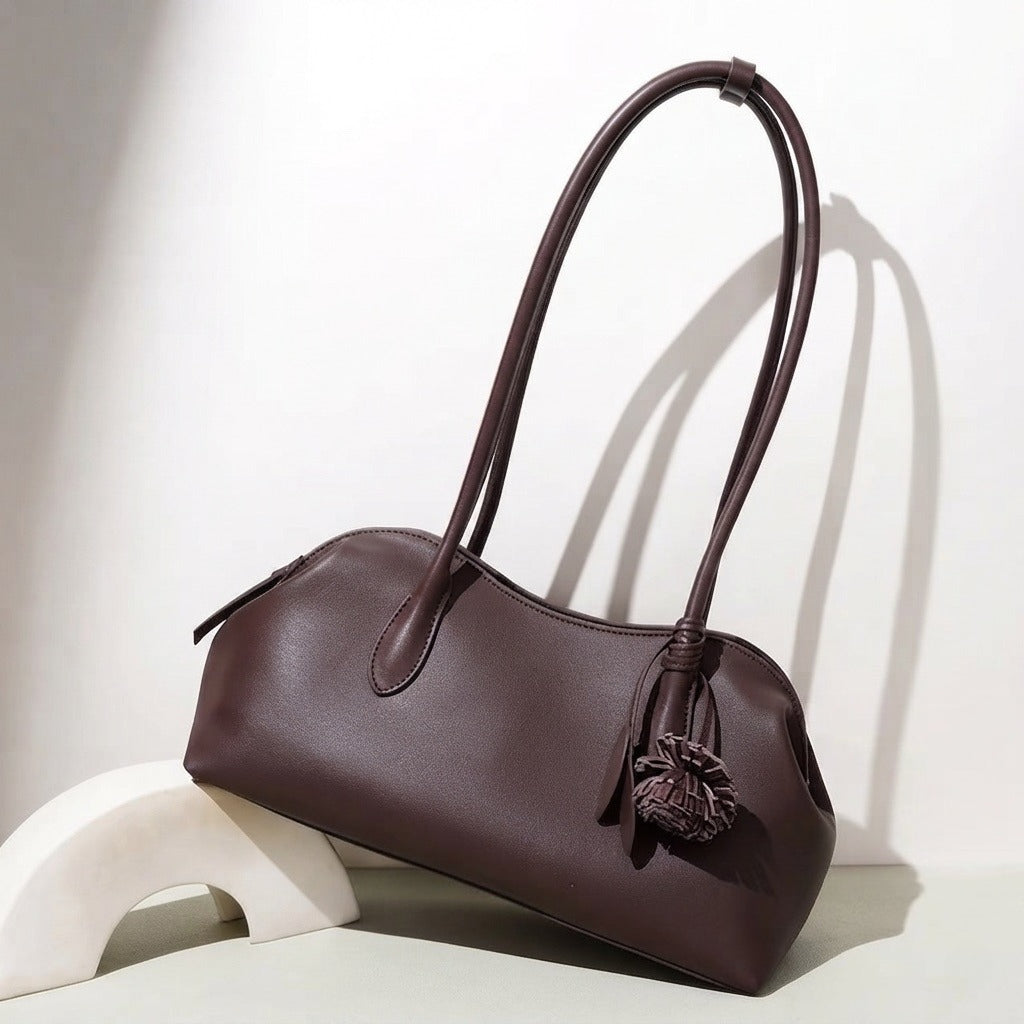 Bolso clutch curvo de piel con charm