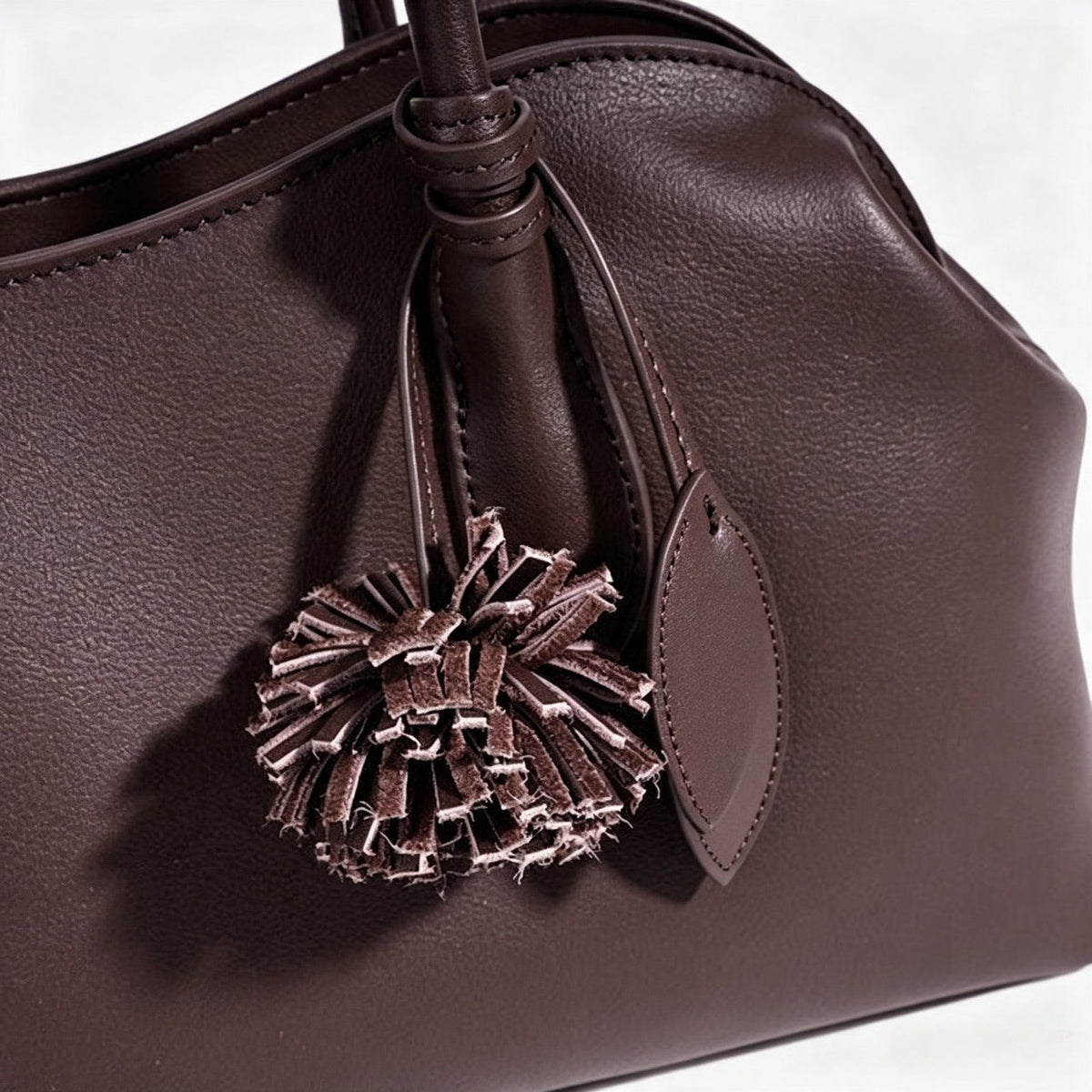 Bolso clutch curvo de piel con charm