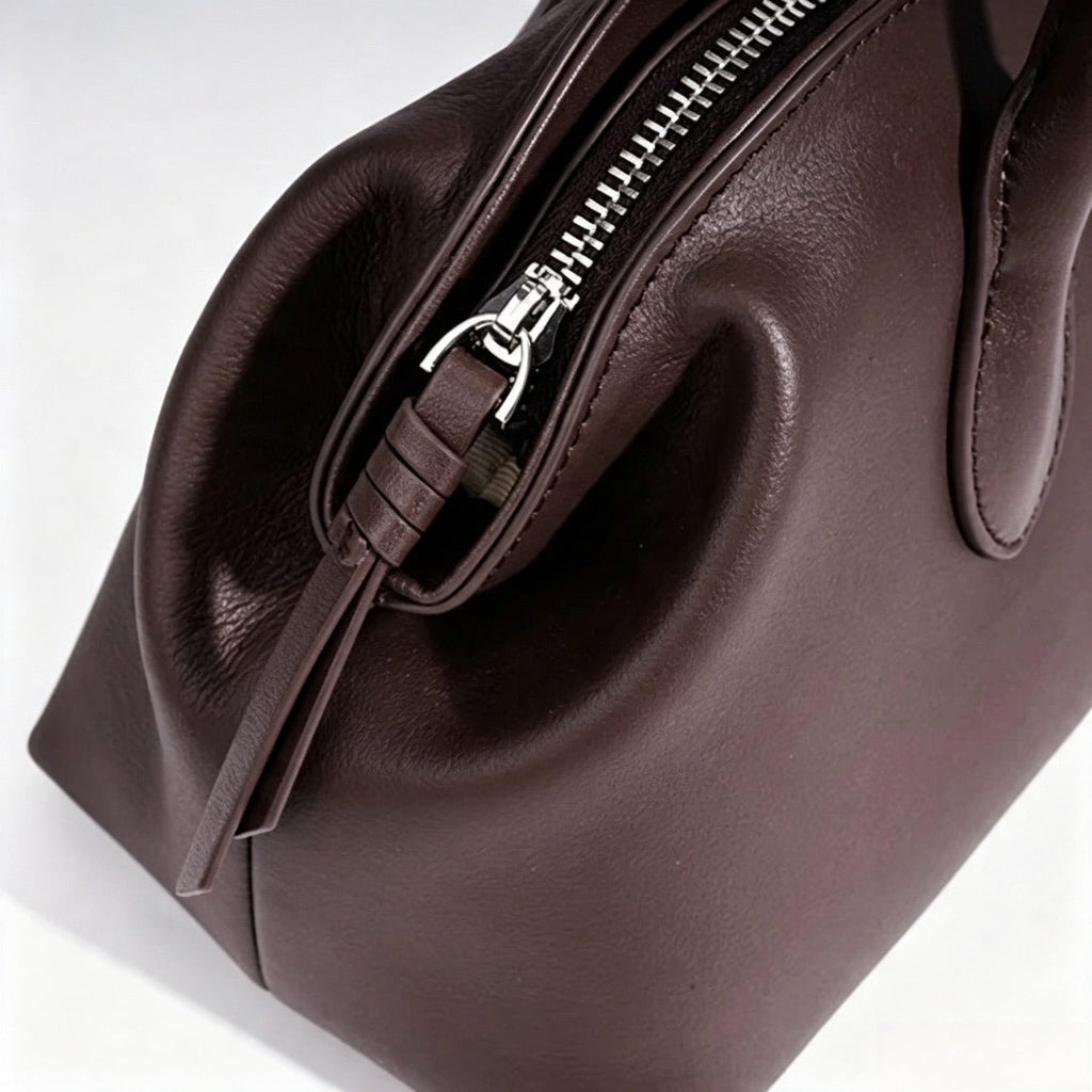Bolso clutch curvo de piel con charm