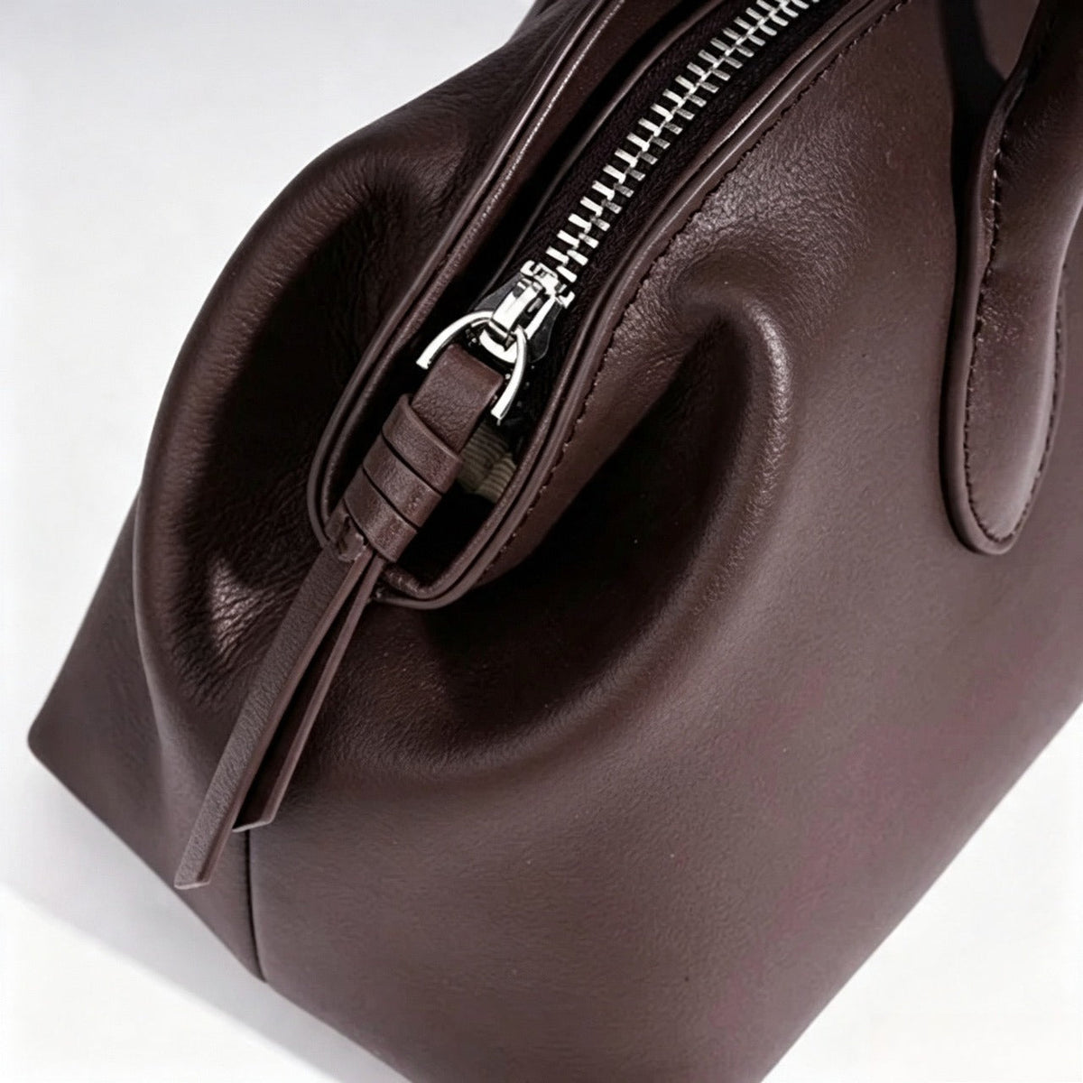 Bolso clutch curvo de piel con charm